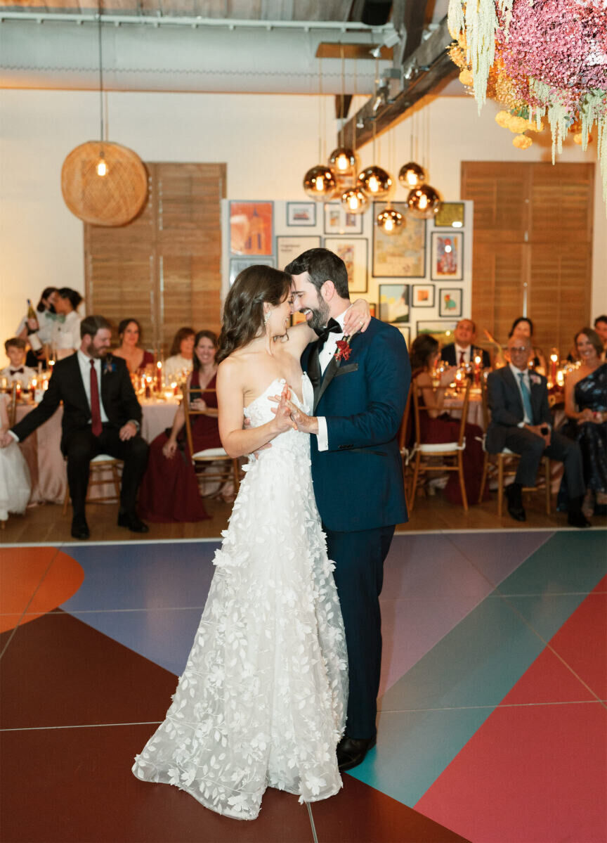Newlyweds dance on a colorfully patterned dance floor during their art-inspired wedding reception.