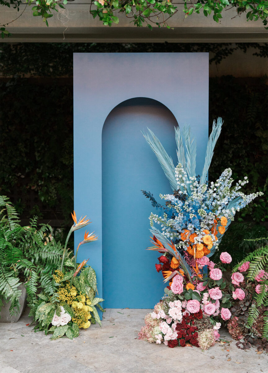 A blue arched panel with two colorful floral arrangements anchored an art-inspired wedding ceremony in Charleston.