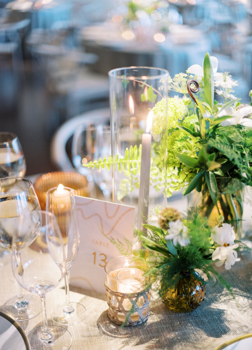 A mix of candles and small arrangements of greenery and white flowers decorated the tables at a enchanted waterfront wedding.