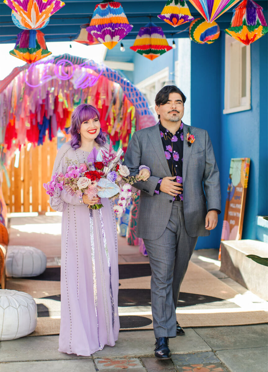 A couple processes to their vibrant outdoor wedding ceremony together.