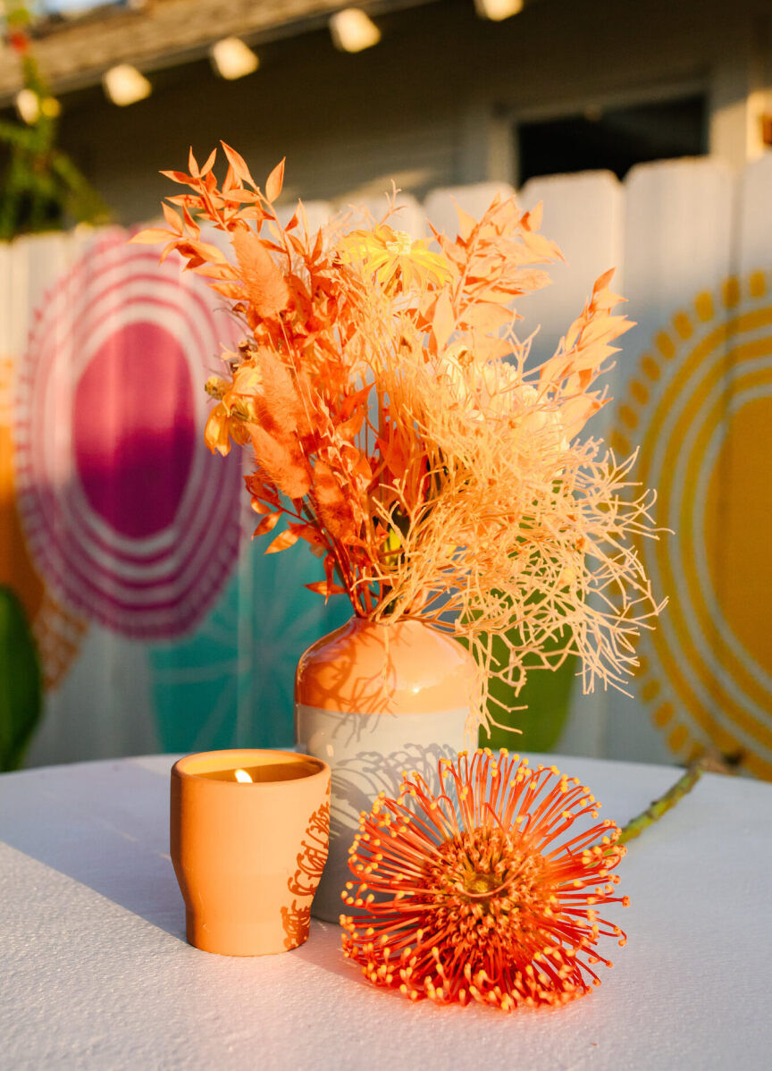 The flowers at this vibrant outdoor wedding were displayed in a mix of handcrafted vessels and incorporated some dried elements for additional texture.