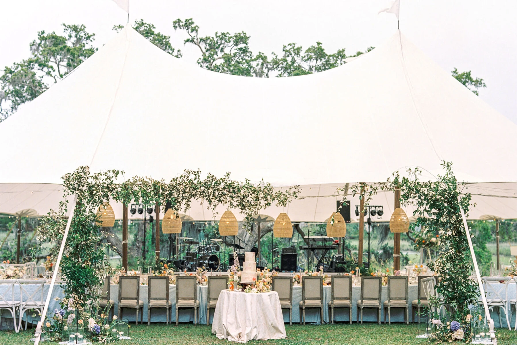 The reception of an elegant spring wedding took place under a sailcloth tent decorated with flowers and greenery at the entrance.